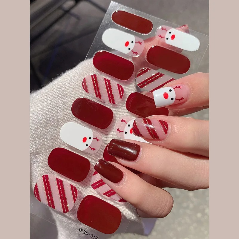  Semi-cured gel nail strips featuring reindeer and snowflakes in pink and red for a subtle holiday theme.

